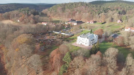 Big-White-Mansion-Aerial,-Villa-in-Rolling-Countryside-on-Sunny-Day