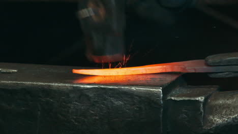 Macro-shot-of-Forge-hammering-on-glowing-iron-inside-workshop