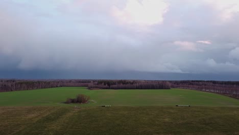 Autumn-storm-clouds-gliding-above-countryside-landscape-aerial-view