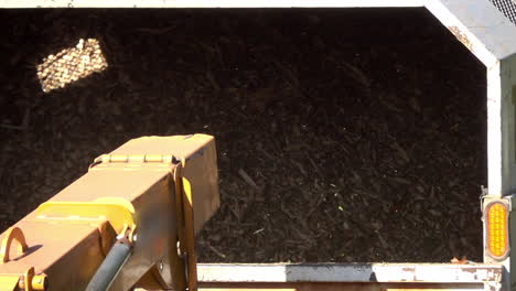 Slow-motion-shot-of-wood-chips-expelled-from-the-chute-of-a-wood-chipper-into-the-back-of-a-truck
