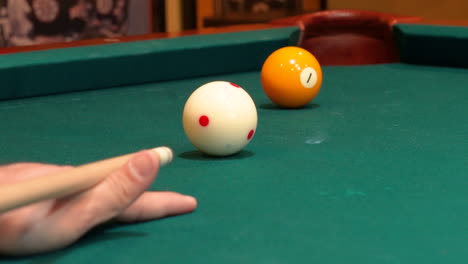Person-Playing-Pool-Shoots-Yellow-Solid-1-Ball-into-Corner-Pocket-with-Cue-Ball-Drawing-or-Spinning-Backwards-Towards-Camera-after-Stroke,-Closeup-Open-Bridge-Hand-with-Wooden-Cue-Stick-and-Green-Felt