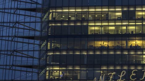 Close-up-people-working-in-modern-glass-office-building,-dusk-time-lapse,-Berlin
