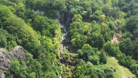 Aerial-dolly-shot-pulling-away-from-a-grand-tiered-waterfall-in-Sopotnica,-Serbia