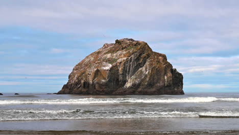 Salpicar-Las-Olas-Del-Mar-Con-Formación-Rocosa-Contra-El-Cielo-Azul-En-Face-Rock,-Bandon,-Oregon