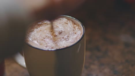 Hot-Chocolate-Drink-In-A-Mug-Being-Stirred-With-A-Teaspoon-For-Breakfast---close-up