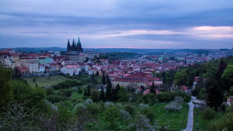 Night-to-day-sunrise-timelapse-in-Prague,-Czech-Republic-as-seen-from-Strahov-gardens-with-a-view-of-Prague-Castle,-Malá-strana-and-downtown-in-the-distance-as-the-morning-sunshine-lights-up-the-city
