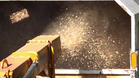 Close-up-of-wood-chips-expelled-from-the-chute-of-wood-chipper-into-the-back-of-a-truck-in-slow-motion