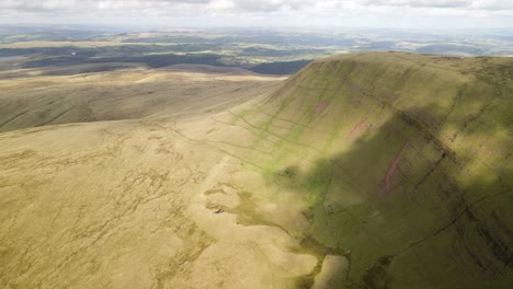 Cloud-shadows-passing-over-Brecon-Beacons-Llyn-y-Fan-Fach-green-mountain-valley-aerial-forward-moving