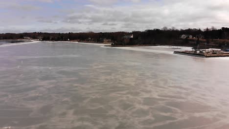 Long-low-advancing-aerial-of-ice-frozen-on-shore-of-Hingham-Harbor