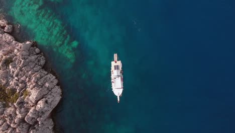Boot-Treiben-Im-Blauen-Meerwasser-In-Phaselis,-Antikes-Lykien---Antalya,-Türkei---Antenne-Von-Oben-Nach-Unten