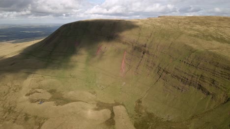 Cloudy-shadows-passing-over-Llyn-y-fan-Fach-Brecon-beacons-green-mountain-wilderness-countryside-aerial-push-in