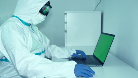 Healthcare-Worker-In-Full-PPE-Working-On-The-Laptop-For-Research-During-Pandemic--medium-shot