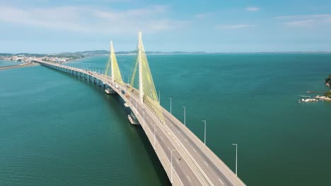 Cinematic-aerial-shot-bridge-traffic-above-the-turquoise-color-ocean,-located-in-Laguna,-Santa-Catarina,-Brazil
