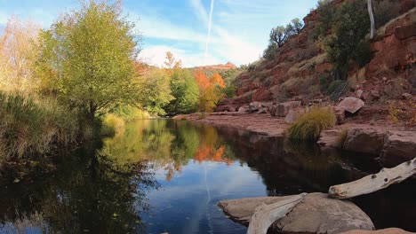 The-water-of-a-slow-moving-creek-reflects-the-magnificent-fall-foliage-and-red-rock-of-Northern-Arizona