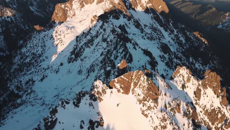 Un-Dron-Mirando-Hacia-Abajo-De-Un-Pico-Nevado-En-Las-Montañas-Olímpicas-Tomado-Desde-Las-Afueras-Del-Parque-Nacional-Al-Atardecer