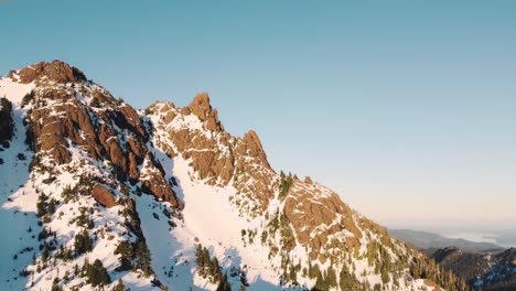 Eine-Aufsteigende-Drohnenaufnahme-Eines-Schneebedeckten-Gipfels-In-Den-Olympischen-Bergen,-Aufgenommen-Direkt-Außerhalb-Des-Nationalparks-Bei-Sonnenuntergang