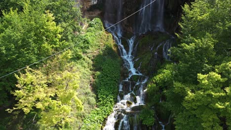 Aerial-shot-rising-up-a-grand-tiered-waterfall-in-Sopotnica,-Serbia-on-a-bright-day