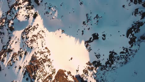 A-wide-top-down-drone-shot-of-a-snowy-peak-in-the-Olympic-mountains-taken-from-just-outside-the-national-park-at-sunset