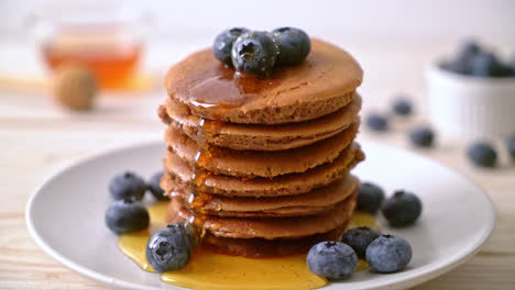 chocolate-pancake-stack-with-blueberry-and-honey-on-plate