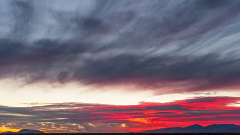 Bright-red-and-hot-pink-light-streaks-across-clouds-in-sunset-timelapse
