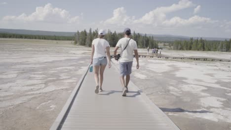 Dos-Personas-Caminando-En-El-Paseo-Marítimo-De-Grand-Prismatic-Springs-En-El-Parque-Nacional-De-Yellowstone