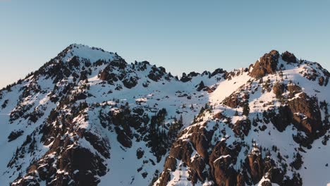 Una-Foto-De-Un-Dron-Ascendente-De-Un-Pico-Nevado-En-Las-Montañas-Olímpicas-Tomada-Desde-Las-Afueras-Del-Parque-Nacional