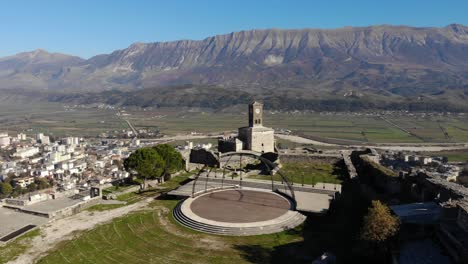 Castle-of-Gjirokastra-in-Albania-with-clock-tower-and-stone-walls-over-the-city,-mountain-background