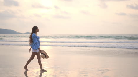 Young-Asian-woman-walks-on-seashore-at-sunset