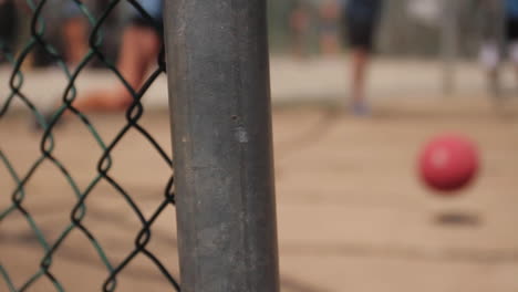 Woman-Kicks-Kickball-in-Background-of-Fence