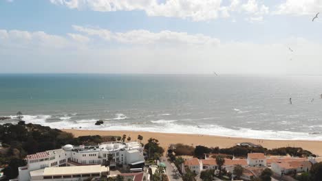 Panoramic-scenic-calm-ocean-shore-with-flying-seagulls-in-Albufeira,-Algarve---Pan-aerial-shot