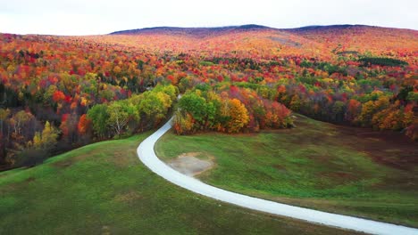 Countryside-Road,-Green-Meadows-and-Magical-Vivid-Forest-With-Colorful-Foliage,-Vermont-USA,-Drone-Shot