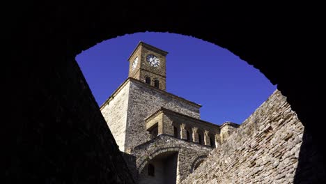 Turm-Der-Uhr-über-Mittelalterlichem-Steingebäude,-Gesehen-Von-Gewölbten-Mauern-Der-Burg-Von-Gjirokastra