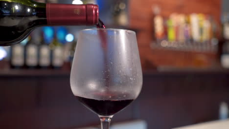 Red-wine-pours-into-glass,-bartender-slowly-fills-wine-goblet,-slow-motion-slider----4K