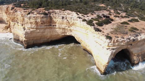 Marinha-beach-eroded-cliffs-in-Benagil-village-in-Algarve,-Portugal---Low-angle-Panoramic-Aerial-shot