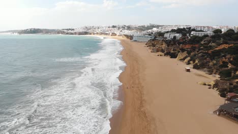 Mediterranean-Beach-line-on-sunny-day-in-Albufeira,-Algarve,-Portugal---Fly-over-Aerial-shot