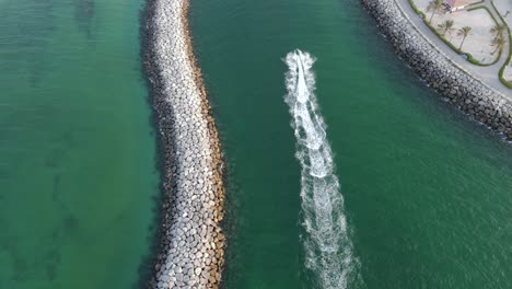 Drone-Camera-follows-the-jet-ski,-watersport-at-paradise,-coast-blue-green-crystal-clear-water-of-Dubai's-Mamzar-beach,-Arabian-Sea,-top-tourist-attraction,-4k-Footage