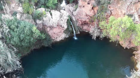 Pego-do-Inferno-waterfall-and-turquoise-lake-in-Tavira,-Algarve,-Portugal---Orbit-Point-of-interest-Aerial