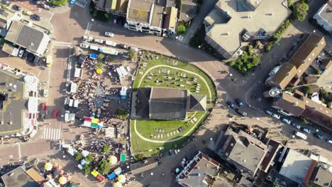Reformed-Church-of-Wijk-aan-Zee-in-the-main-square-with-the-traditional-market,-in-North-Holland,-the-Netherlands---Rotating-Bird's-eye-view