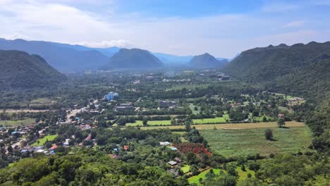 Aerial-4k-drone-footage-flying-into-a-valley-with-a-small-countryside-town-between-mountain-ranges-in-Khao-Yai,-Thailand