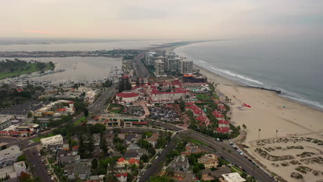 Drone-Approaching-Hotel-del-Coronado-With-Marina-In-Glorietta-Bay-And-Silver-Strand-State-Beach-In-Background-In-California,-USA