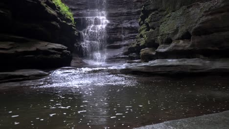 Cascading-water-fall-that-is-pouring-down-into-a-pool-surrounded-by-mossy-smooth-rock-at-Starved-Rock-in-Matthiessen-State-Park