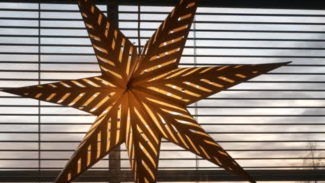 Dark-storm-clouds-drifting-in-behind-christmas-star-decoration-in-window