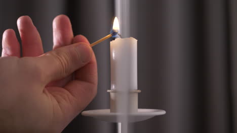 Nahaufnahme-Der-Männlichen-Hand,-Die-Kerze-Auf-Weißem-Hängendem-Kerzenhalter-Anzündet