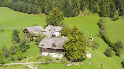 Aerial-orbiting-around-few-chalets-grouped-together-in-clearing,-Alps