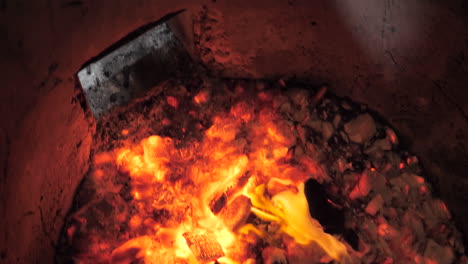 Naan-cooks-over-open-wood-flame-in-clay-pot-tandoor-oven,-slow-motion-slide-close-up----4K