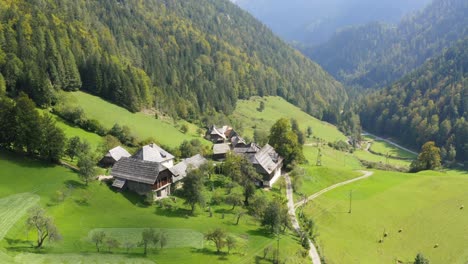 Ariel-shot-of-a-wooden-cabin-in-the-middle-of-a-forest-and-valley,-Črna-na-Koroškem,-Slovenia