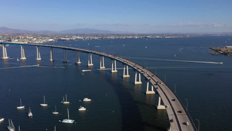 Drone-Flying-Above-Vehicles-Driving-At-Coronado-Bridge-Over-San-Diego-Bay-With-Chula-Vista-And-National-City-In-Background-In-San-Diego-California,-USA