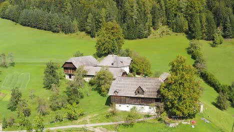 Aerial-View-Over-Wooden-Timber-Building-On-Foot-Of-Forested-Hillside-In-Slovenia