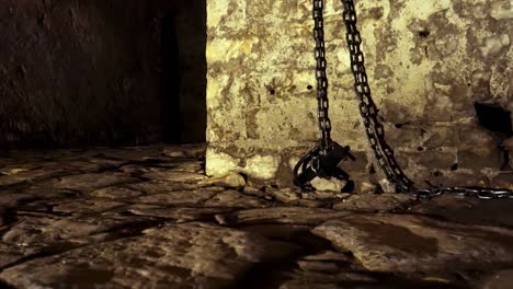Iron-chains-hanged-on-stone-walls-of-dungeon-inside-medieval-castle,-fear-and-terror-scenery
