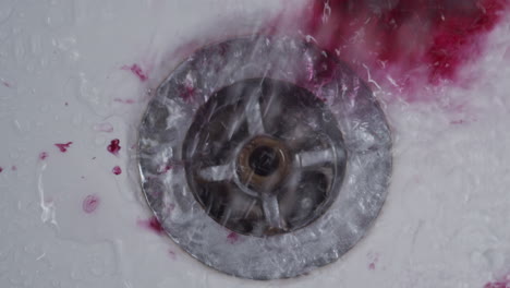 Dark-red-liquid-swirls-with-shower-water-to-rinse-down-bath-drain